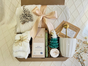 Snowflakes Gift Box by Arinna Gifts featuring a throw blanket, fluffy socks, gourmet chocolate, coffee mug, golden spoon, herbal tea, candle, bath salt, and Christmas ornament.