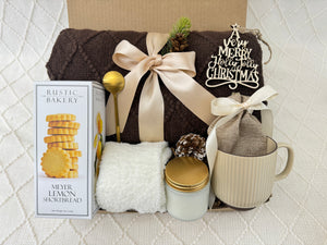 Christmas Morning Gift Box by Arinna Gifts featuring a throw blanket, fluffy socks, gourmet cookie, coffee mug, golden spoon, hot chocolate, scent candle, and Christmas ornament.