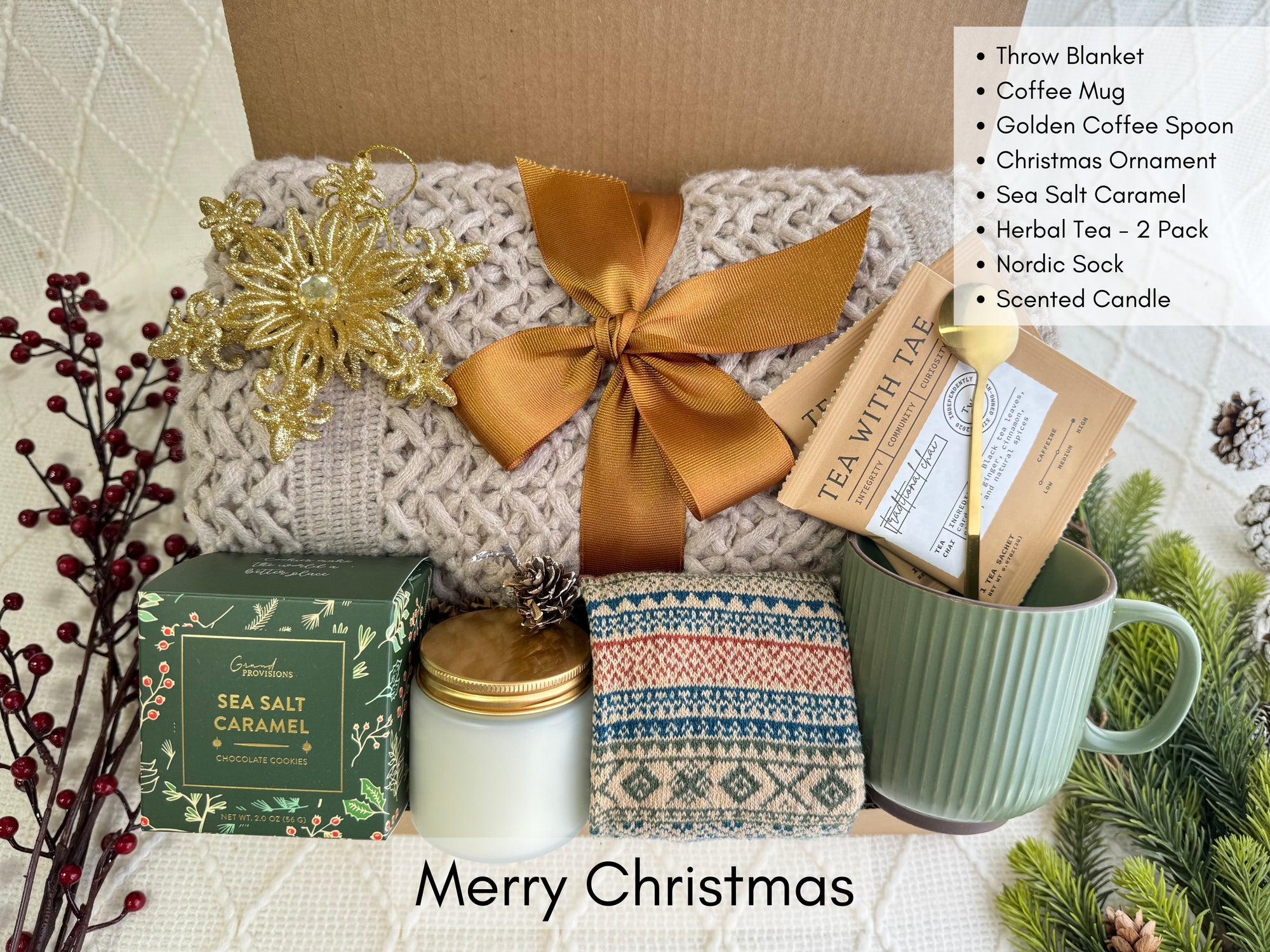 Merry Christmas Gift Box featuring a throw blanket, Nordic socks, gourmet cookie, coffee mug, golden coffee spoon, herbal tea, scent candle, and snowflake Christmas ornament.