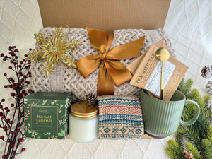 Merry Christmas Gift Box featuring a throw blanket, Nordic socks, gourmet cookie, coffee mug, golden coffee spoon, herbal tea, scent candle, and snowflake Christmas ornament.