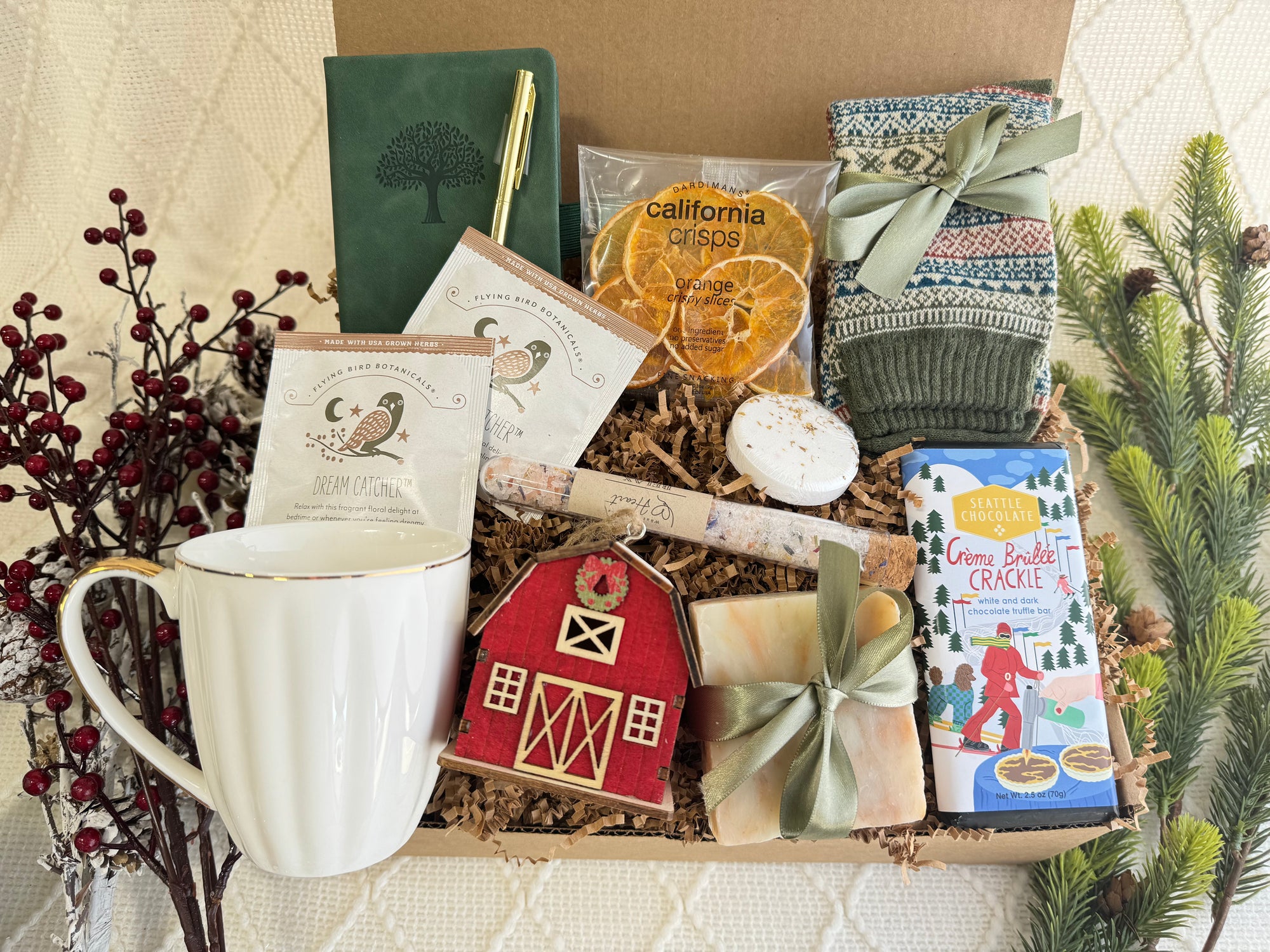 It’s Cold Outside Gift Box featuring a pocket notebook, Nordic socks, dried orange slices, coffee mug, gourmet chocolate, herbal tea, handmade soap, bath salt, shower steamer, wooden house ornament, and golden pen.