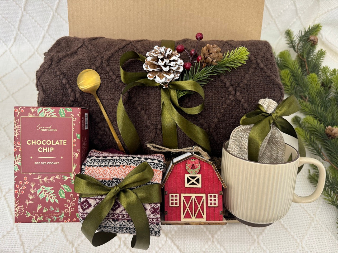 Winter Days Gift Box featuring a throw blanket, Nordic socks, gourmet cookie, coffee mug, golden coffee spoon, wooden house ornament, hot chocolate, and burlap bag.