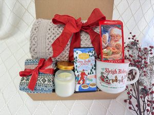 I’ll Be Home Gift Box featuring a throw blanket, Nordic socks, gourmet chocolate, Christmas coffee mug, hot chocolate, and a scent candle.