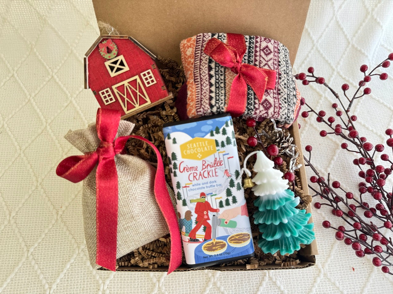 Silver Bells Gift Box featuring Nordic socks, gourmet chocolate, Christmas tree candle, hot chocolate, burlap bag, and wooden house ornament.