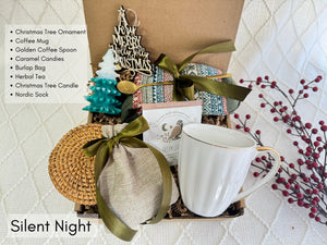 Silent Night Gift Box featuring Nordic socks, coffee mug, herbal tea, burlap bag, wooden Christmas ornament, golden coffee spoon, Christmas tree candle, caramel candy, and coaster.