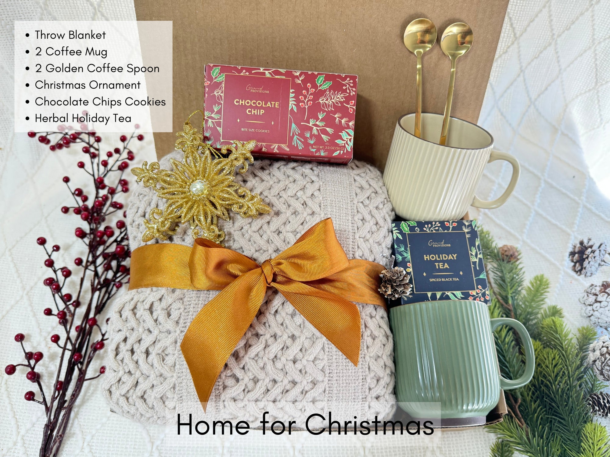 Home for Christmas Gift Box featuring a throw blanket, coffee mug, golden coffee spoon, holiday tea, gourmet cookie, and snowflake Christmas ornament.