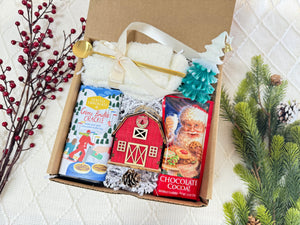 Under My Tree Gift Box featuring white fluffy socks, gourmet chocolate, wooden house ornament, Christmas tree candle, golden coffee spoon, and hot chocolate.